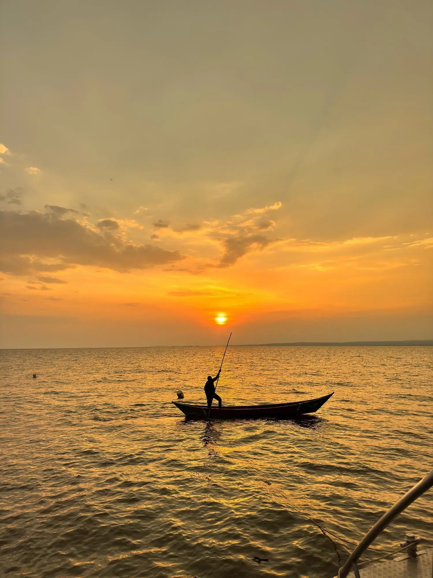 A fisherman poling his boat across Lake Victoria at sunset near Dunga, Kisumu