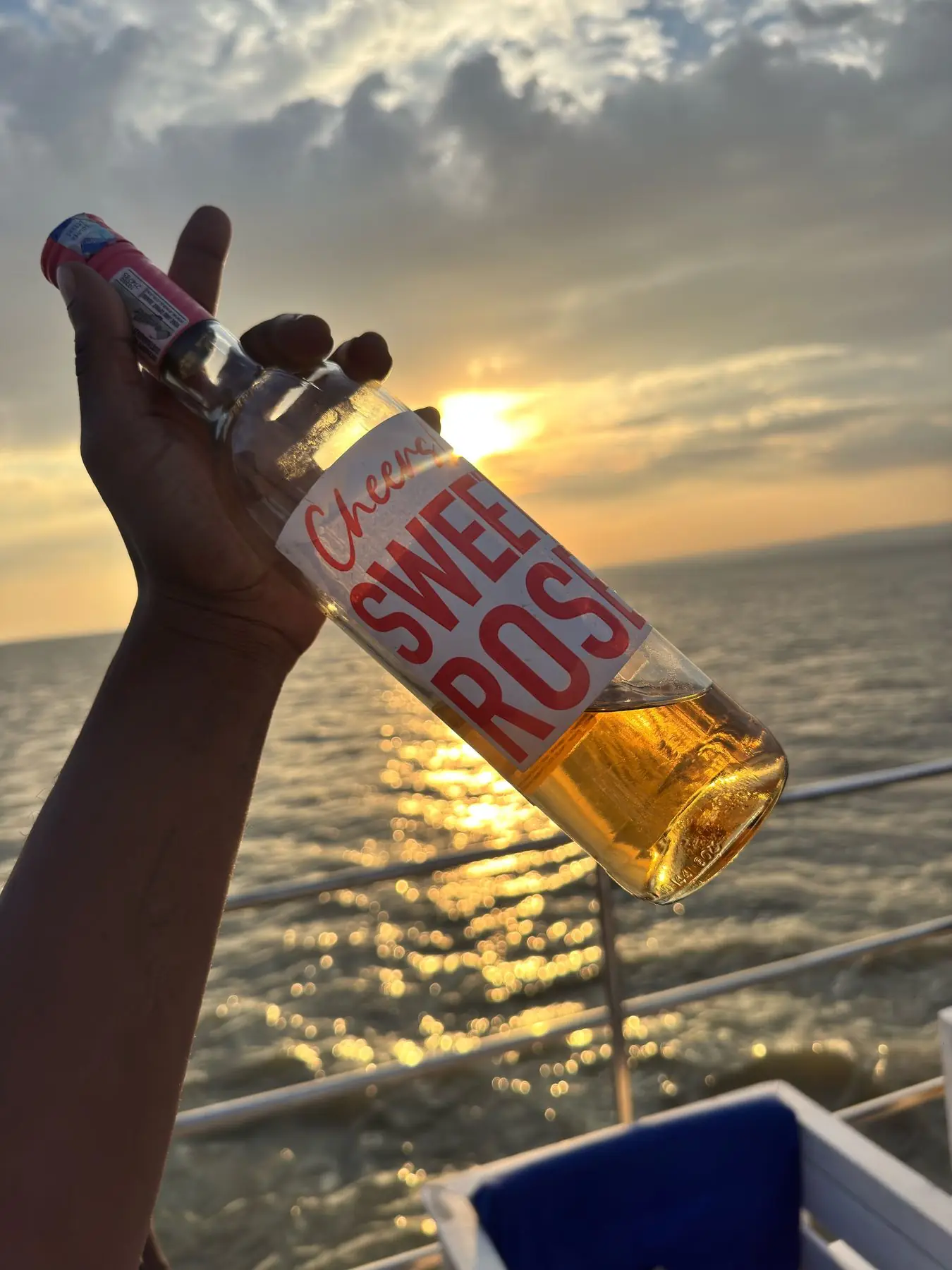 A chilled bottle of rose held against the sunset on Lake Victoria